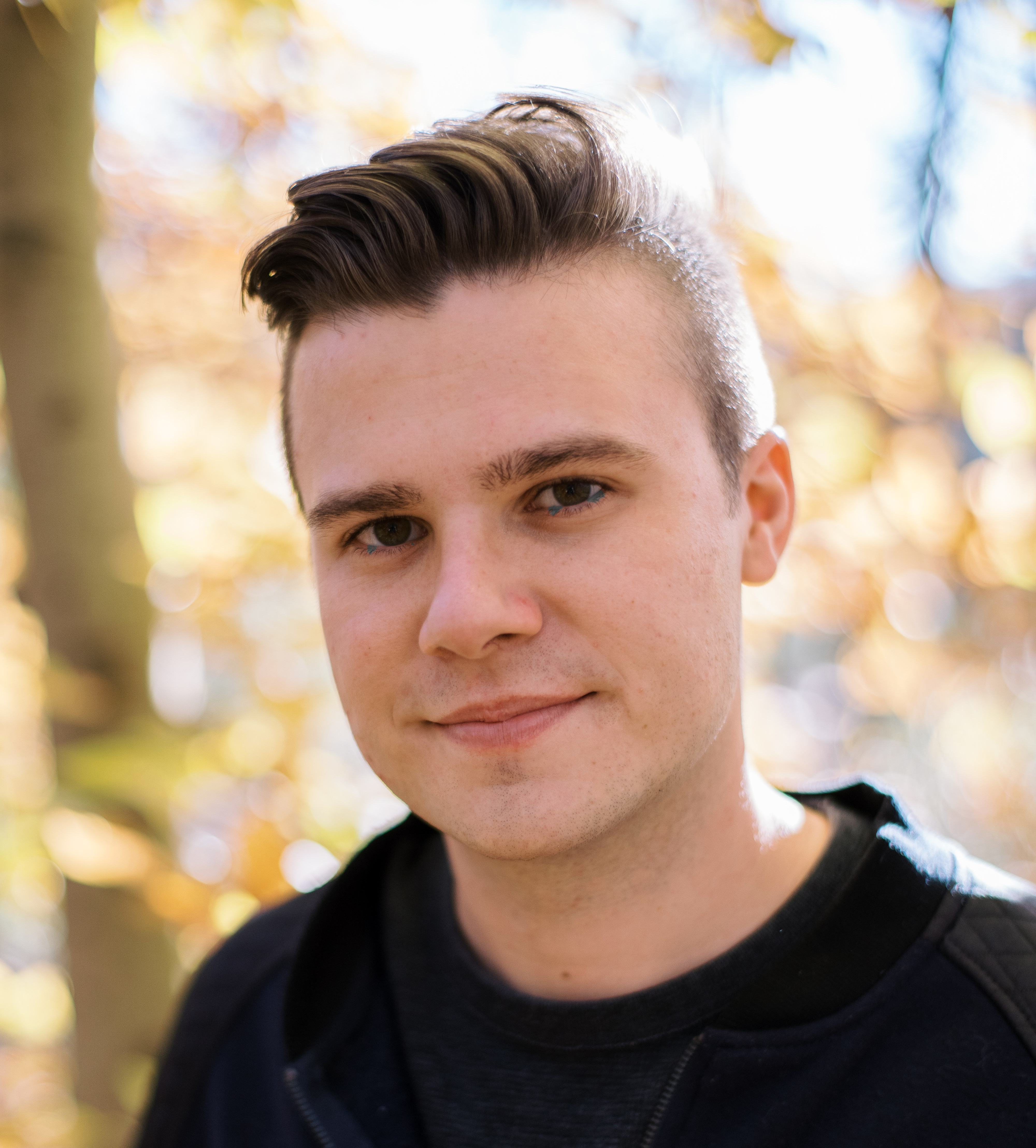 Headshot of man smiling with blurred forest in background
